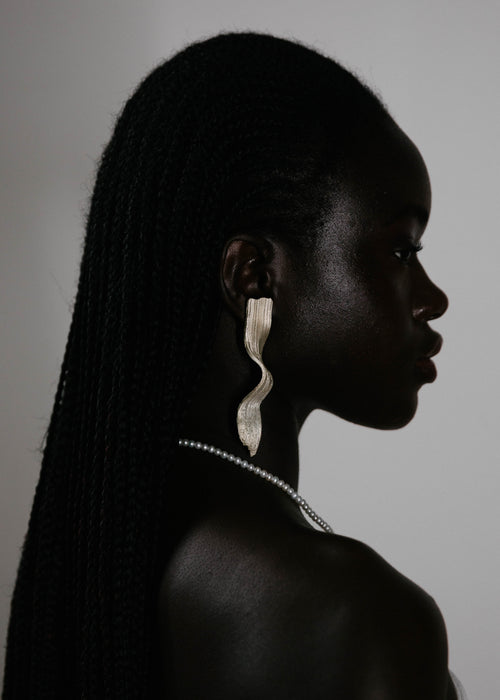 Handcrafted silver earring worn by model with white background