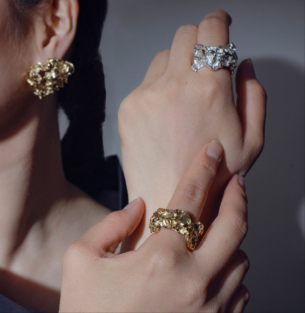 a pair of hands wearing a gold and silver variant of the handcrafted Bellis ring