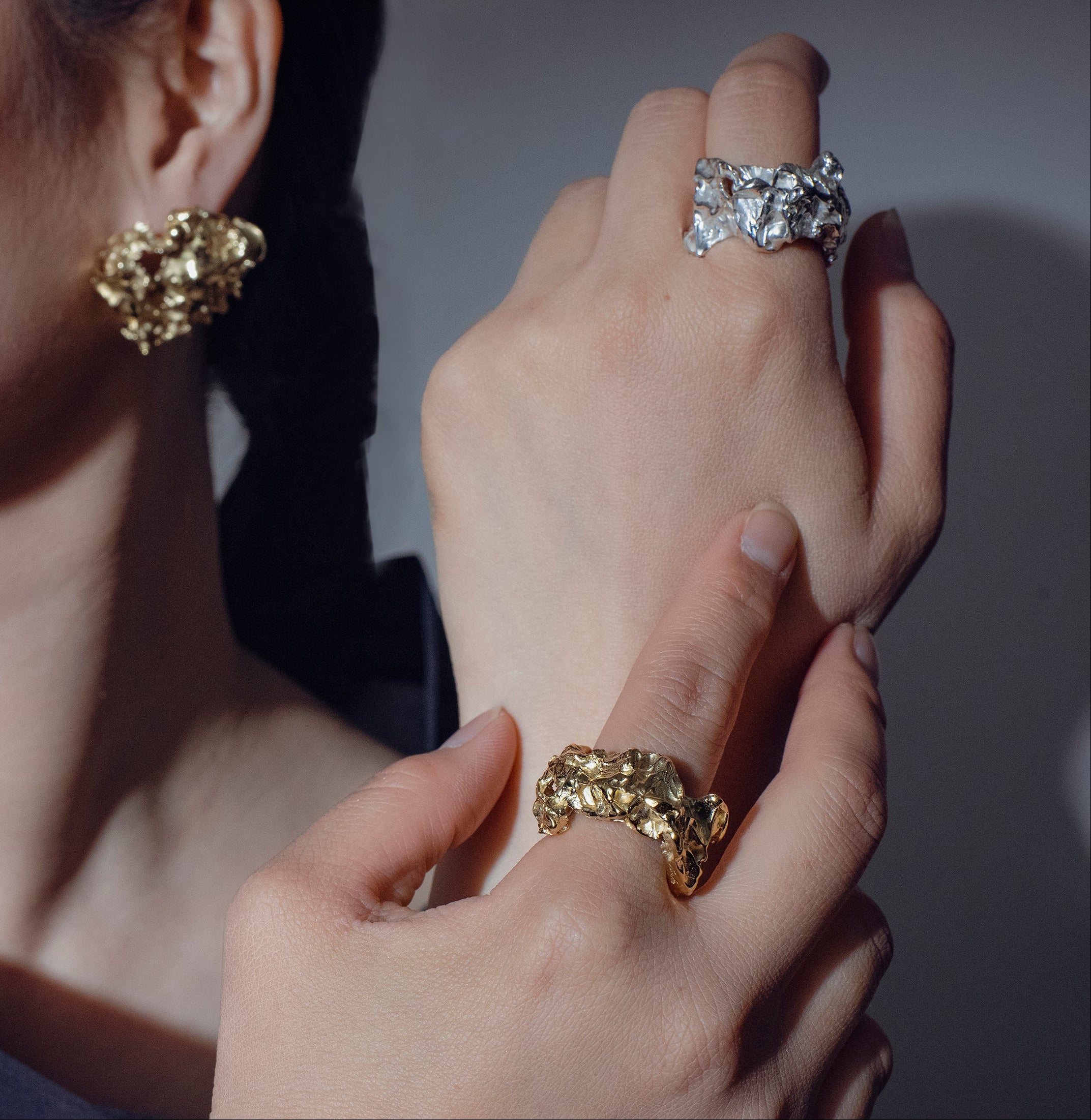 a pair of hands wearing a gold and silver variant of the handcrafted Bellis ring