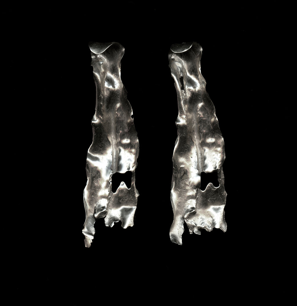 Pair of handcrafted silver earrings on a black background