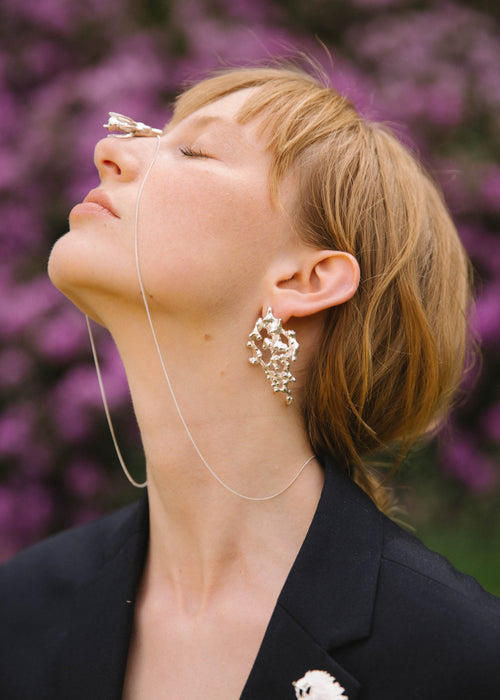 handcrafted confusa earring worn by model with nature background