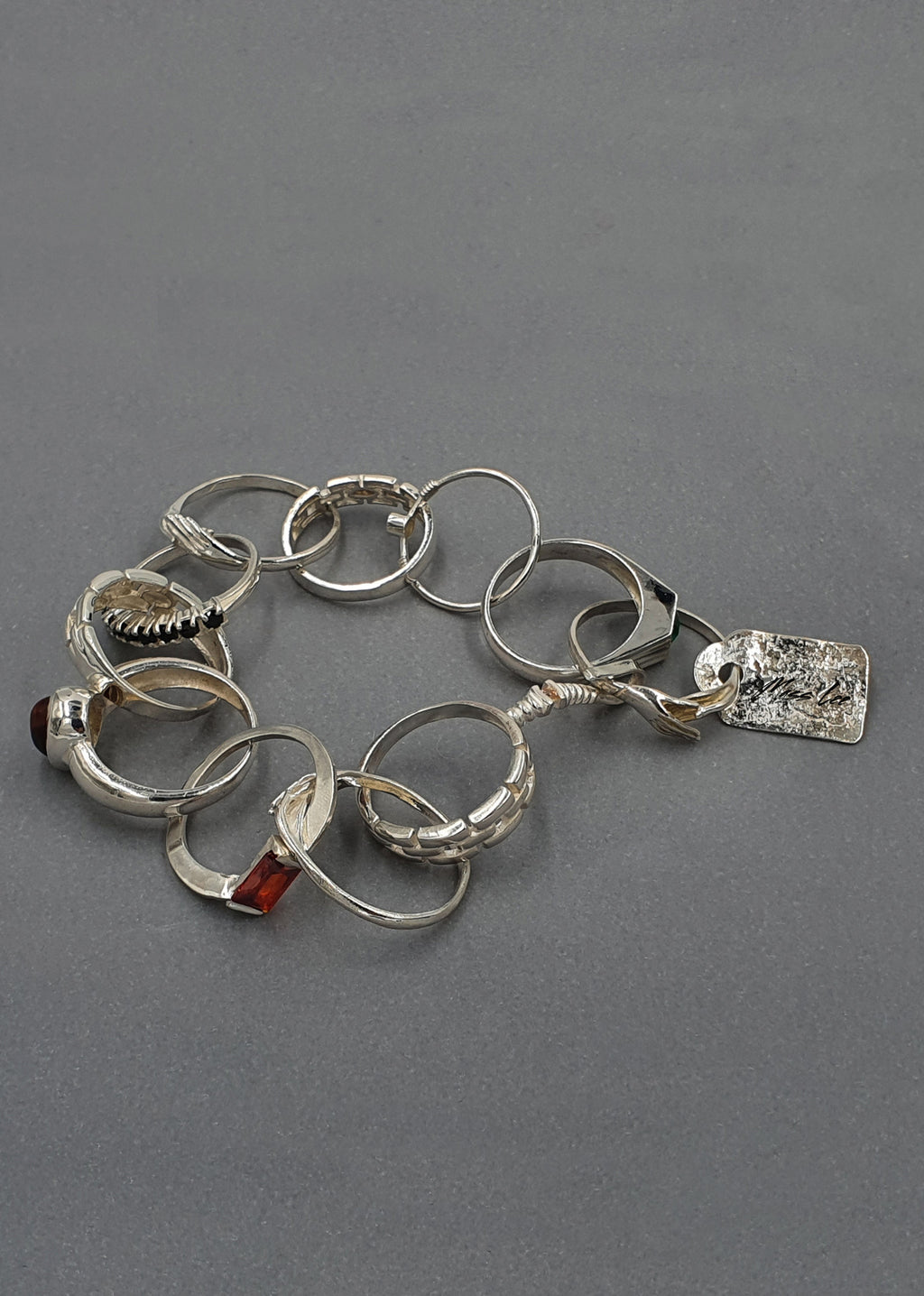 Handcrafted Silver bracelet with various links on a gray background