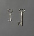 Two handcrafted silver keys on a dark gray background