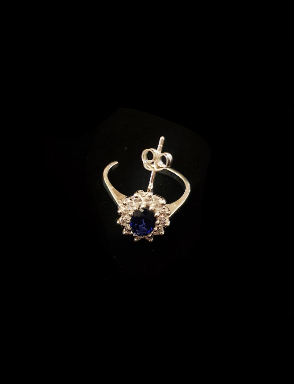 handcrafted silver earring with blue gemstone on black background