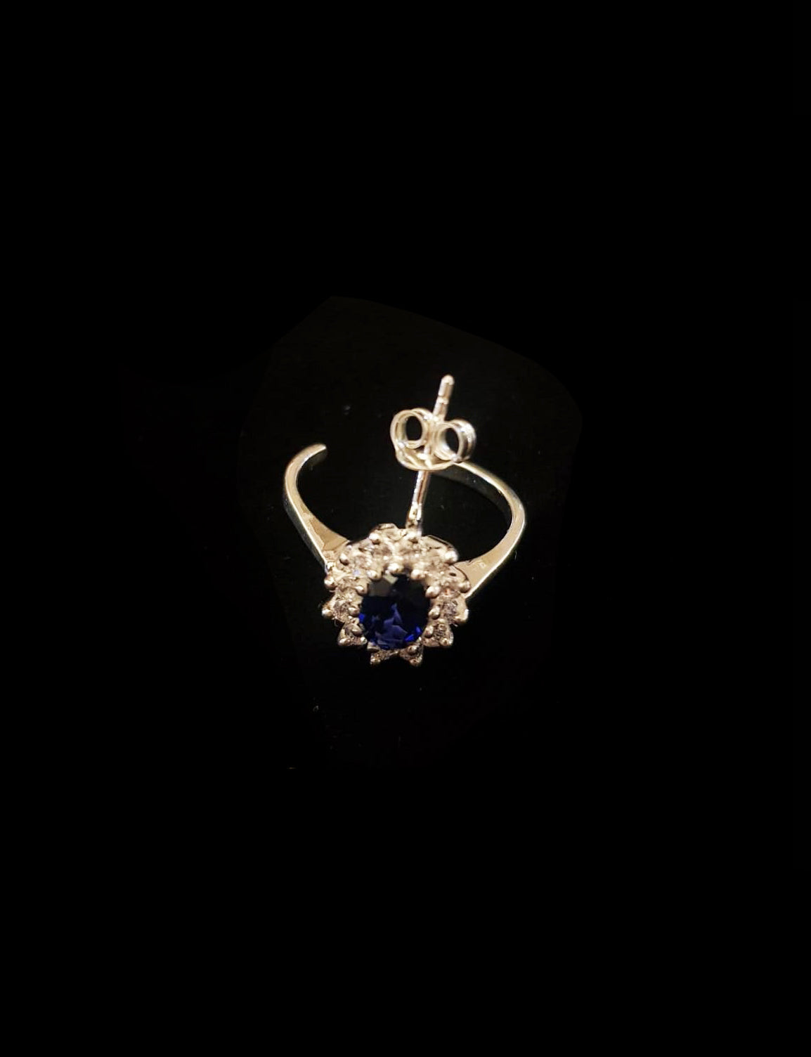 handcrafted silver earring with blue gemstone on black background