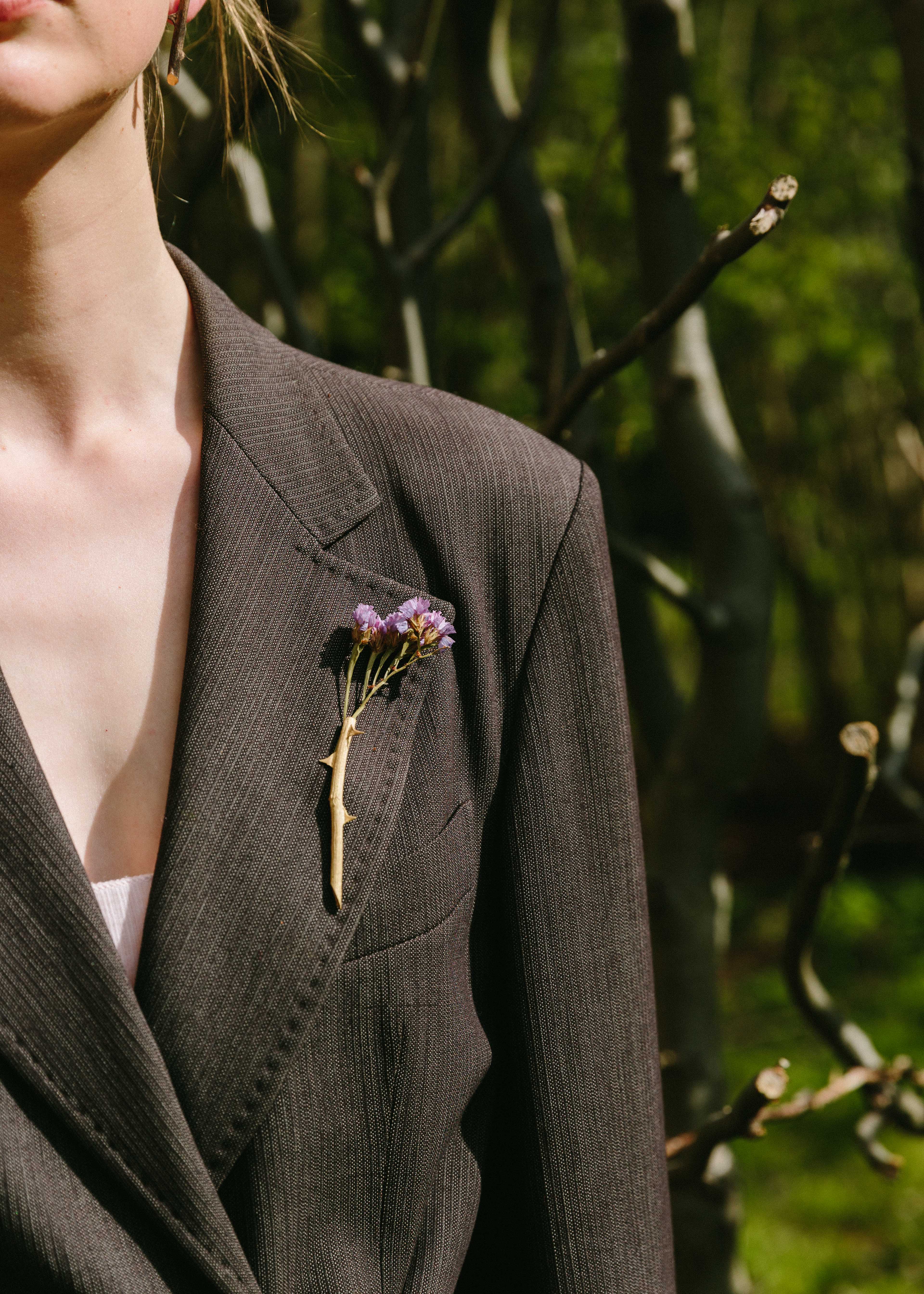 Handcrafted gold rosa brooch with flower inside with nature in background