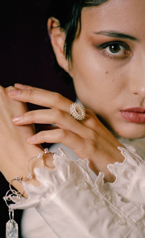 Close-up of a woman wearing a handcrafted ring and bracelets with a dark background