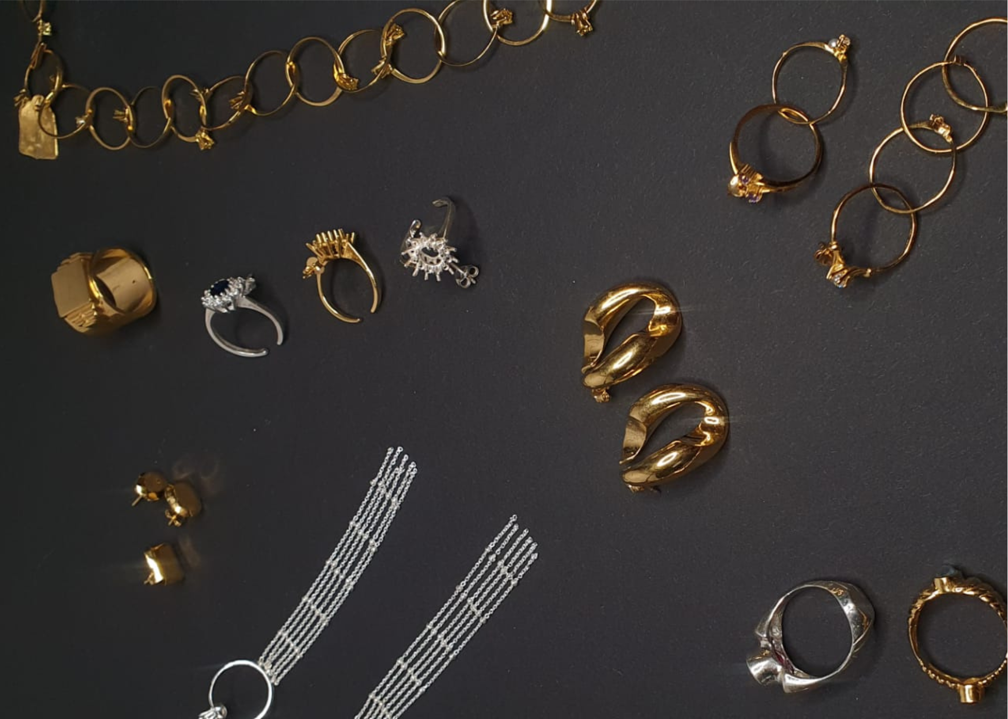 Collection of handcrafted gold and silver jewelry on a dark surface